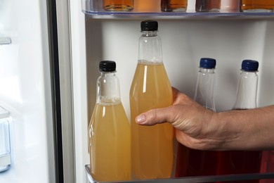 Woman taking bottle with drink from refrigerator, closeup