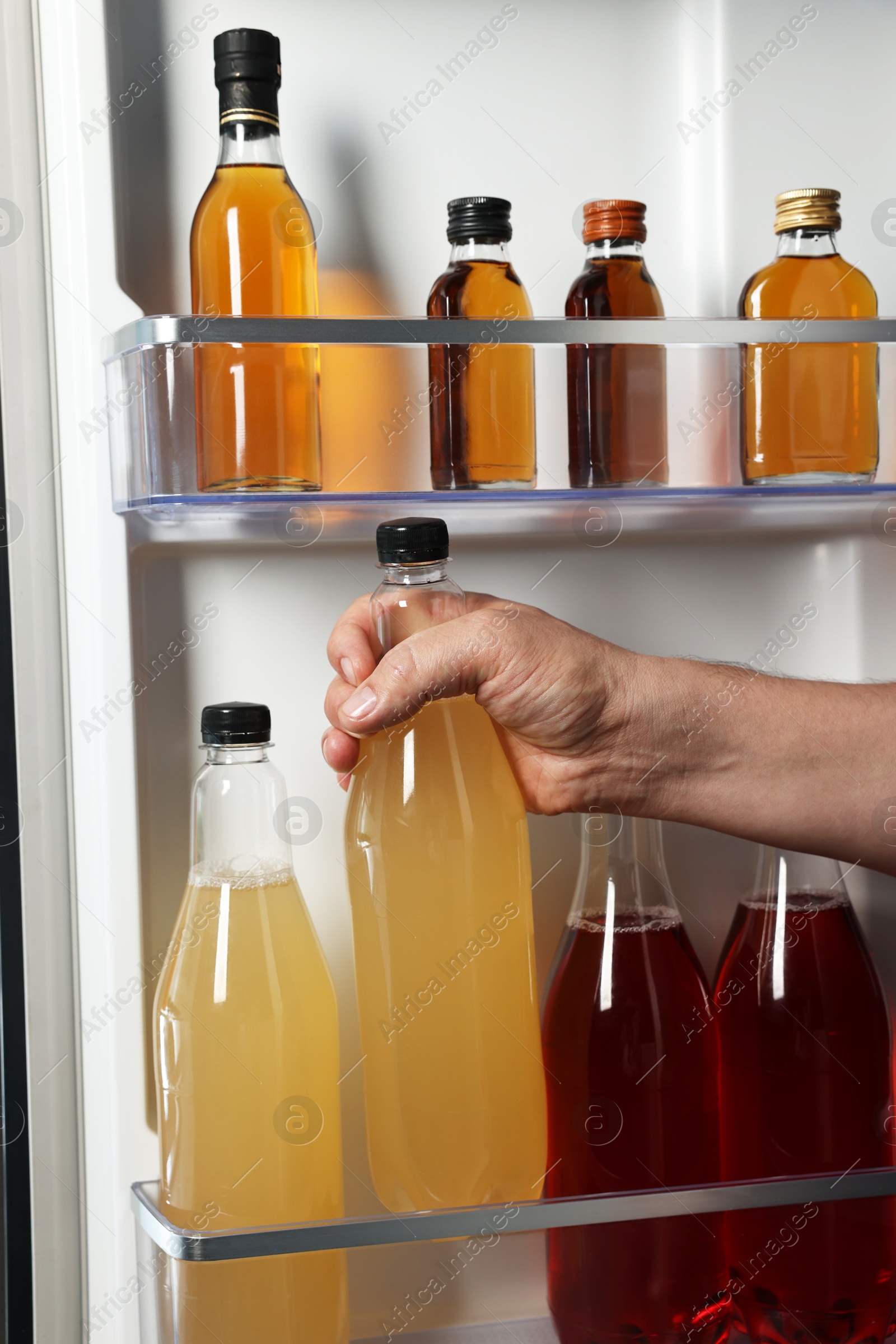 Photo of Woman taking bottle with drink from refrigerator, closeup