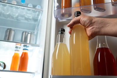 Photo of Woman taking bottle with drink from refrigerator, closeup