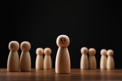 Photo of Loneliness concept. Human figure alone among others on wooden table