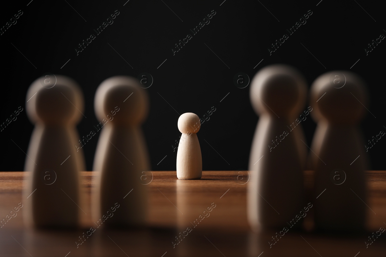 Photo of Loneliness concept. Human figure alone among others on wooden table