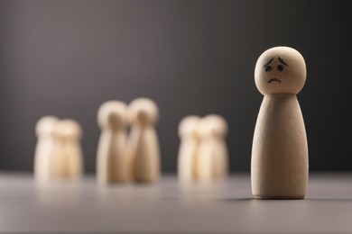 Photo of Loneliness concept. Human figure with sad face distant from others on grey background