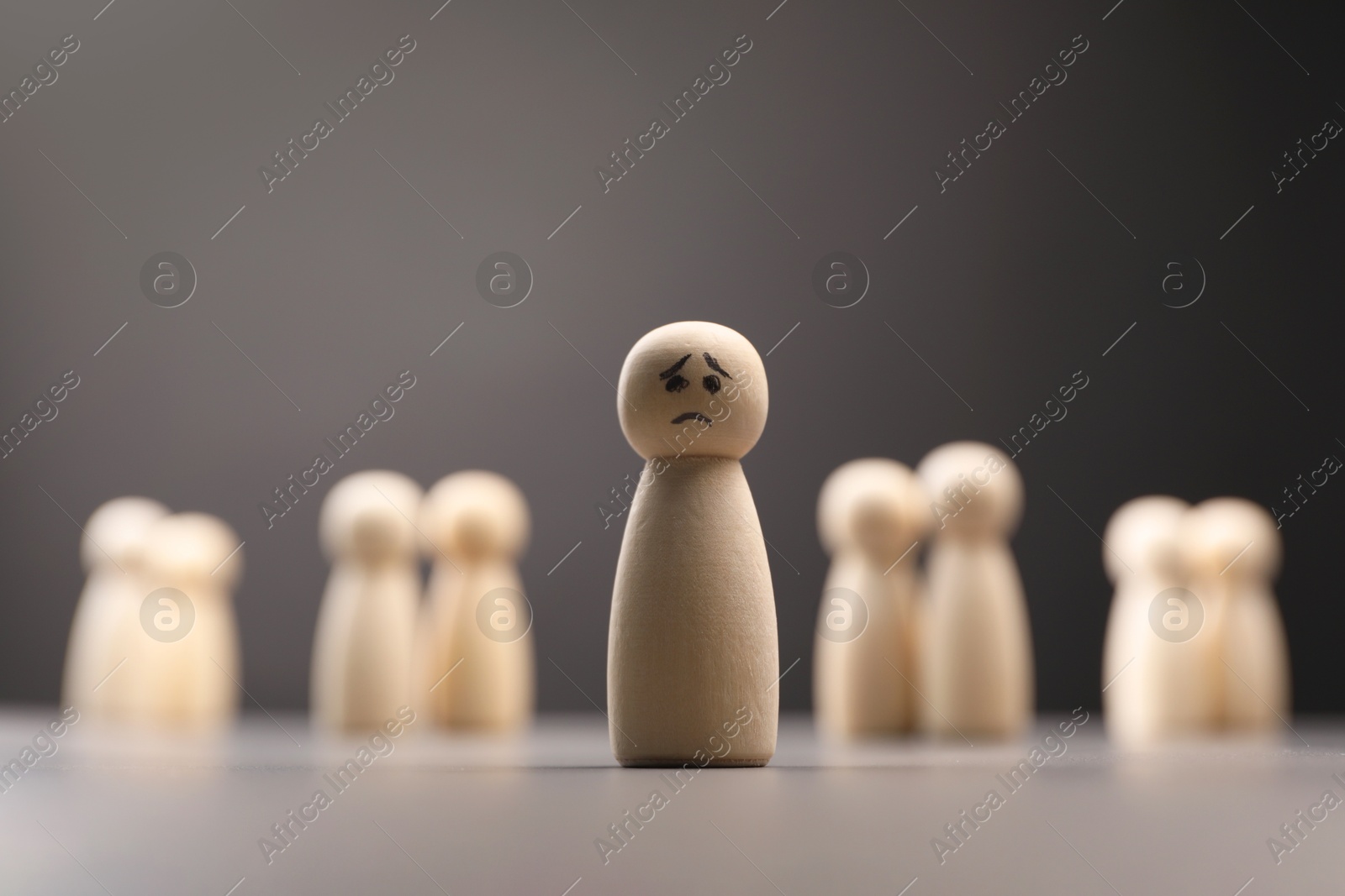 Photo of Loneliness concept. Human figure with sad face distant from others on grey background