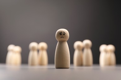 Photo of Loneliness concept. Human figure with sad face distant from others on grey background