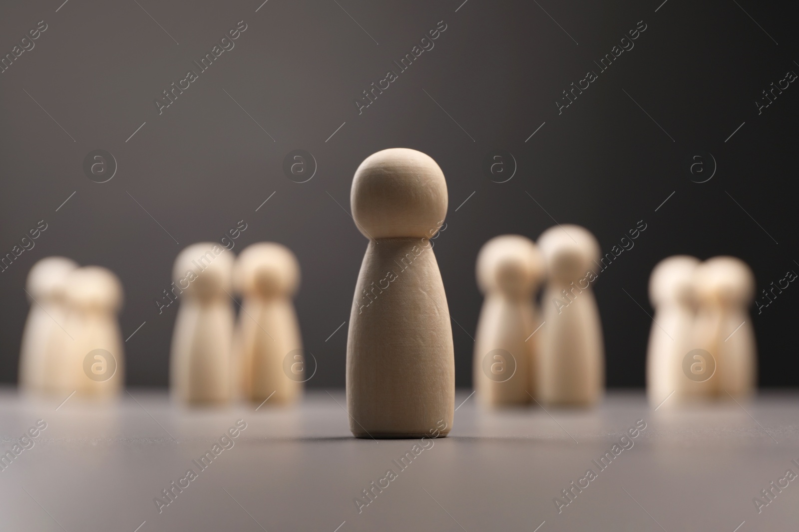 Photo of Loneliness concept. Human figure distant from others on grey background