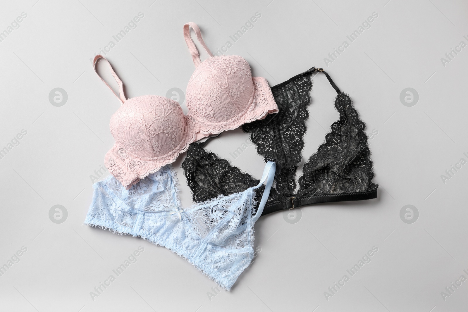 Photo of Different lace bras on grey background, top view