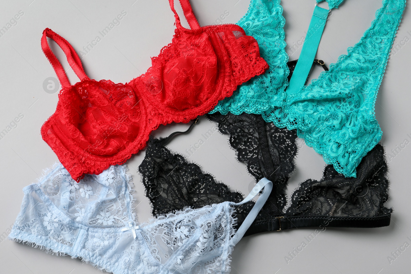 Photo of Different lace bras on grey background, top view