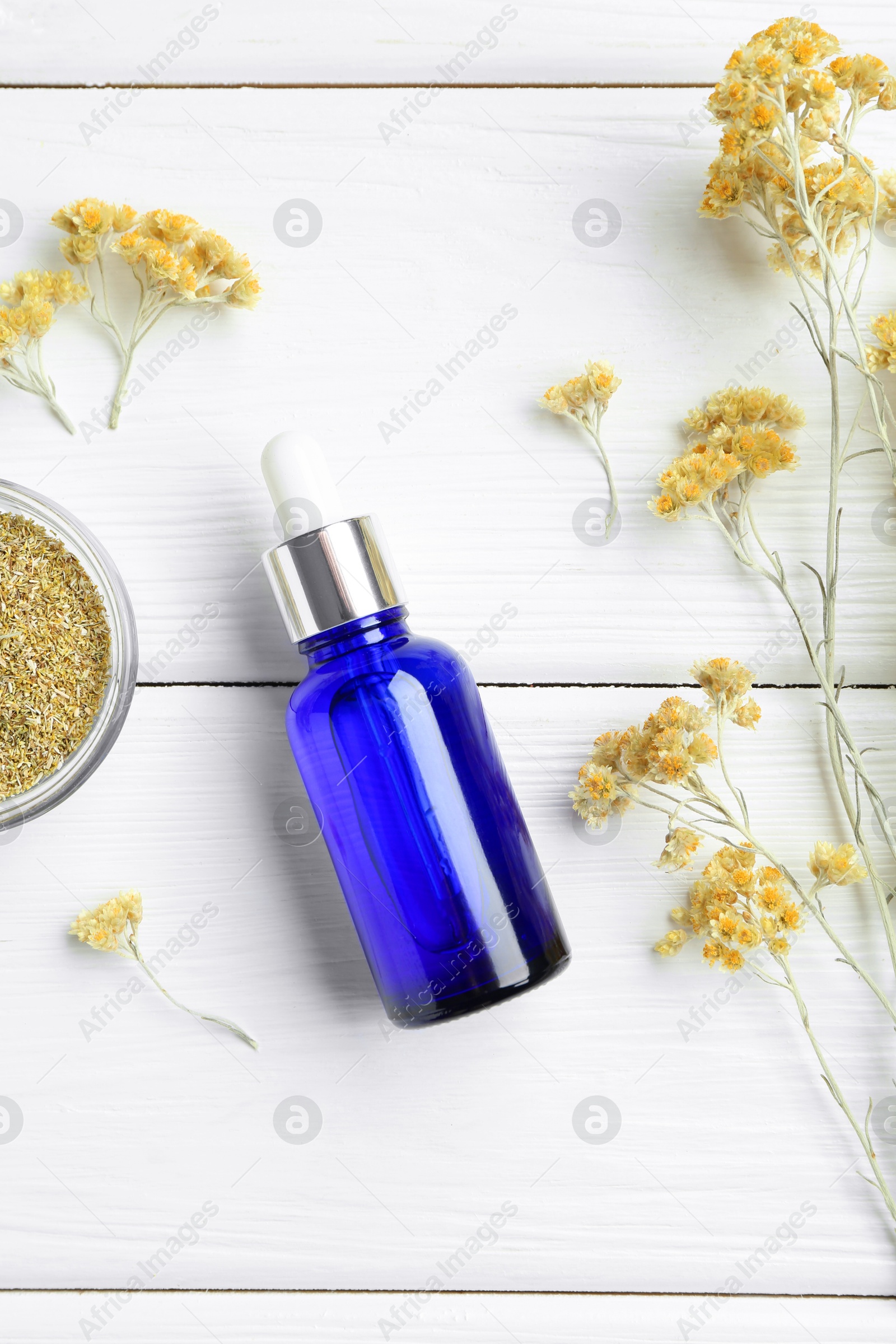 Photo of Bottle of tincture and helichrysum flowers on white wooden table, flat lay