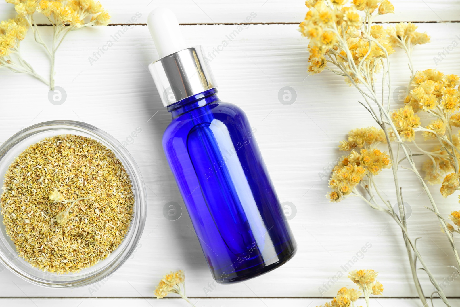 Photo of Bottle of tincture and helichrysum flowers on white wooden table, flat lay