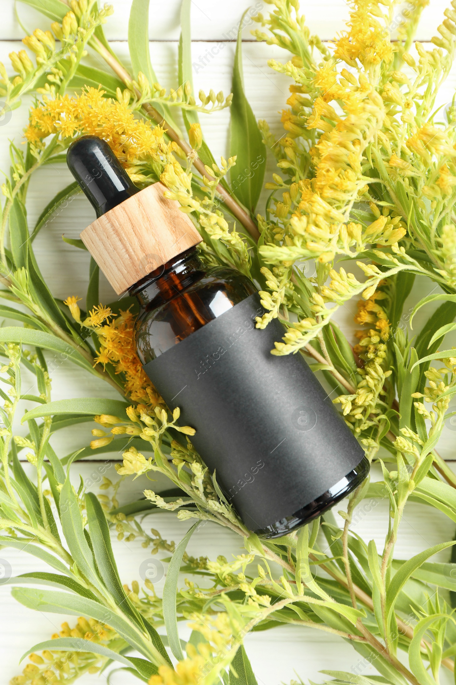 Photo of Bottle of tincture and goldenrods flowers on white wooden table, flat lay