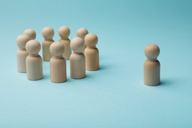 Photo of Loneliness concept. Human figure distant from others on light blue background