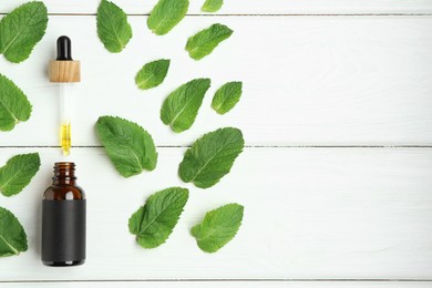 Dripping tincture from pipette into bottle and mint on white wooden table, flat lay. Space for text