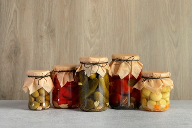 Photo of Different pickled products in jars on grey table