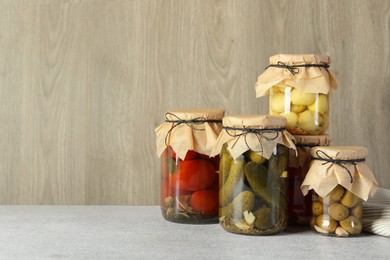 Photo of Different pickled products in jars on grey table, space for text