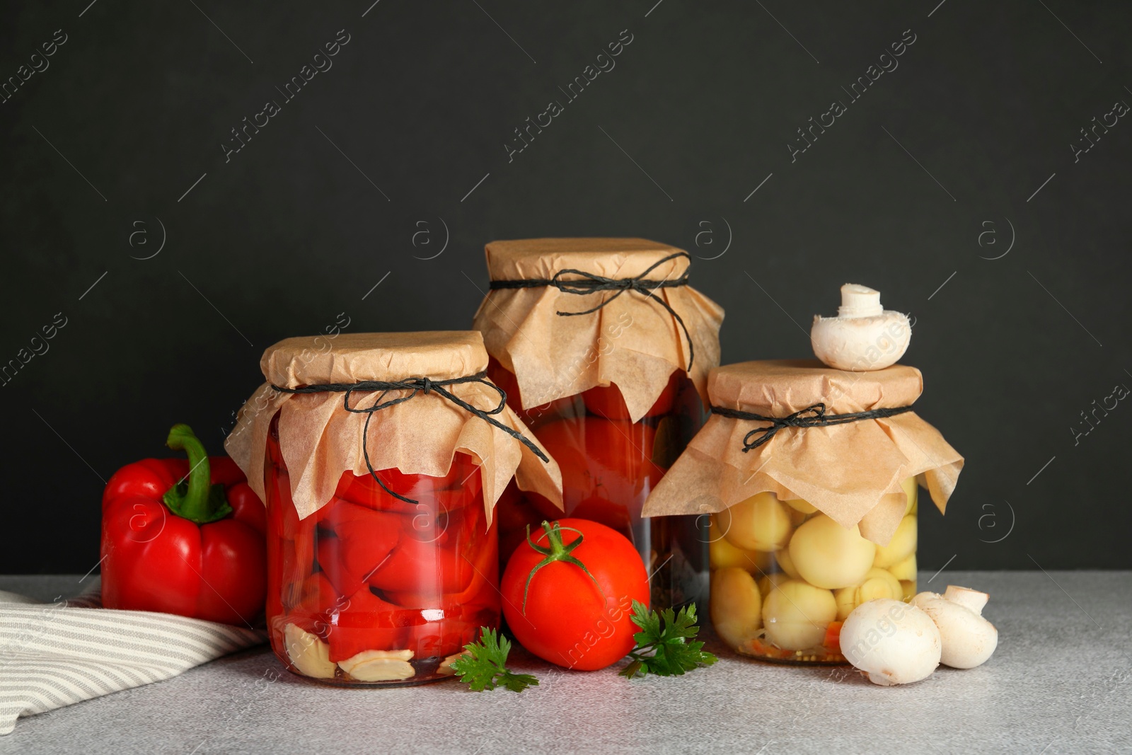 Photo of Different pickled products in jars and fresh ingredients on grey table