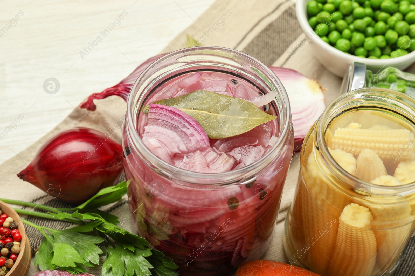 Photo of Different pickled products in jars and fresh ingredients on white table