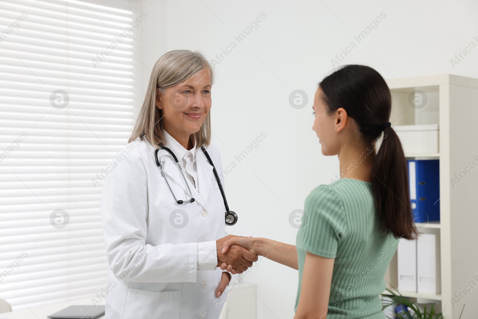 Photo of Senior doctor shaking hands with patient in hospital