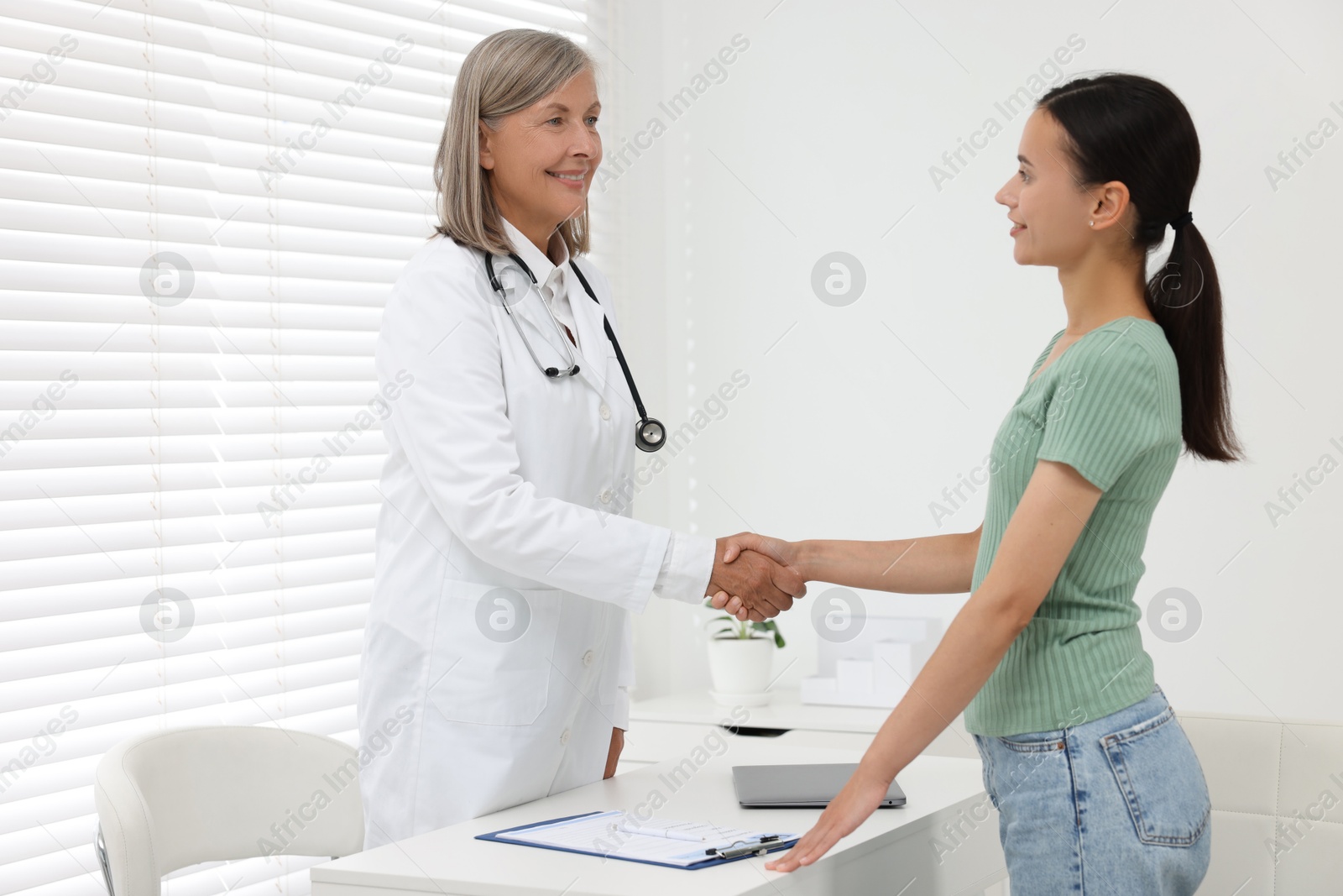 Photo of Senior doctor shaking hands with patient in hospital