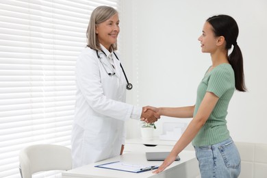 Senior doctor shaking hands with patient in hospital