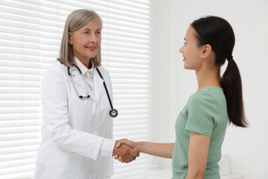 Photo of Senior doctor shaking hands with patient in hospital