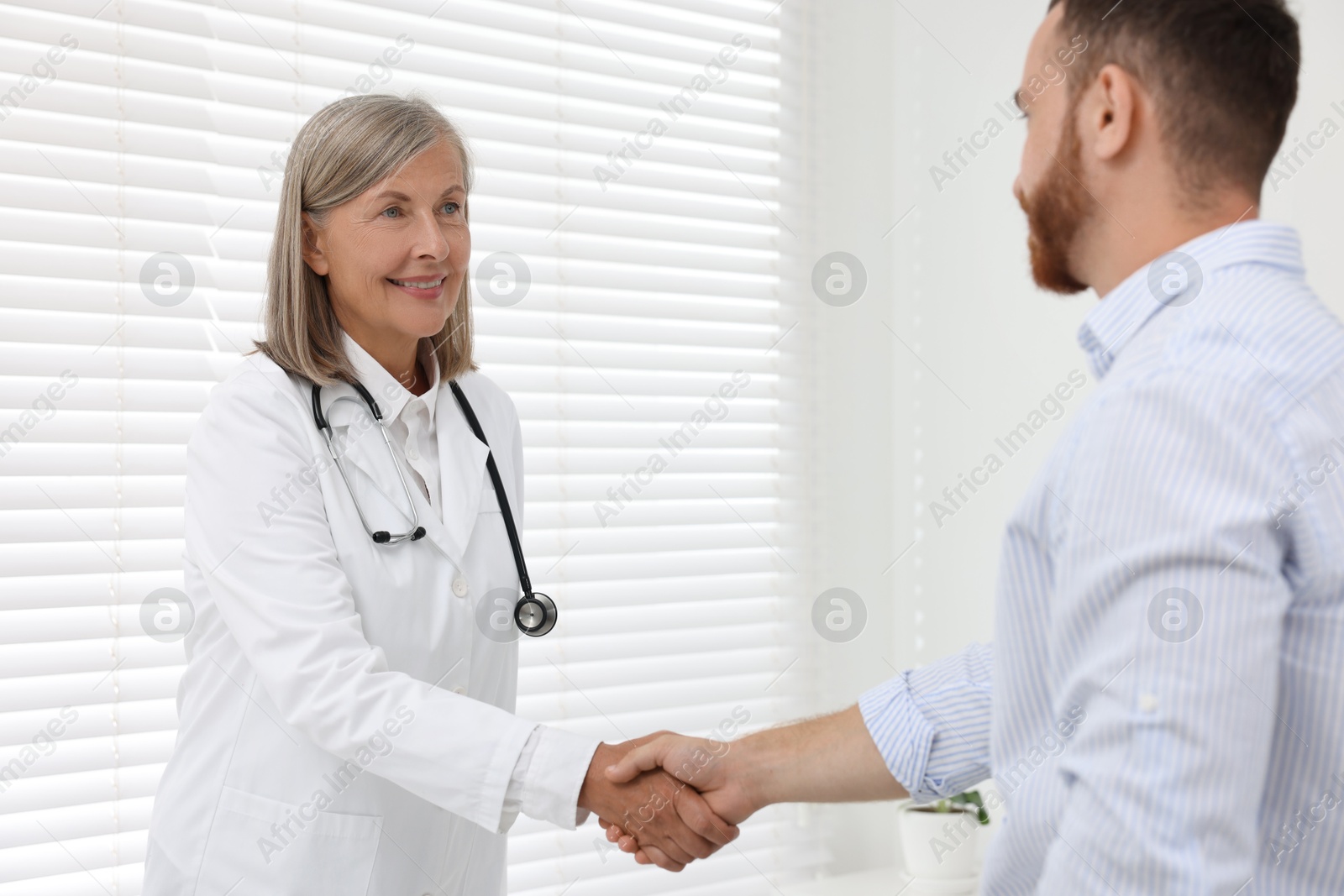 Photo of Senior doctor shaking hands with patient in hospital