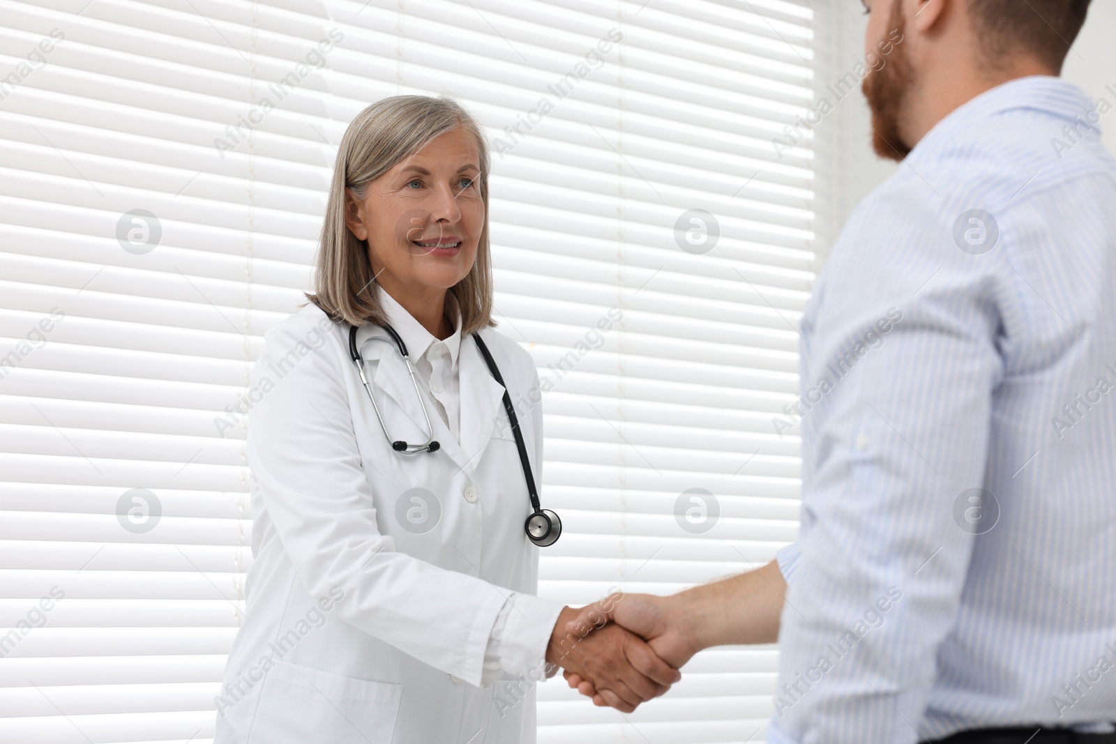 Photo of Senior doctor shaking hands with patient in hospital