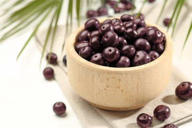 Photo of Ripe acai berries in bowl on white table, closeup