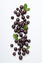 Ripe acai berries and leaves on white background, flat lay