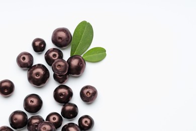 Photo of Ripe acai berries and leaves on white background, flat lay. Space for text