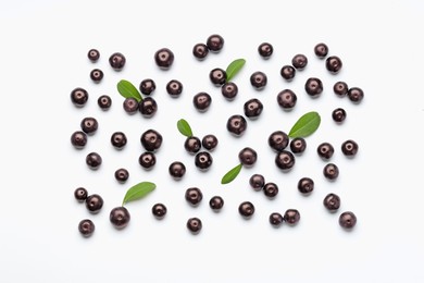 Photo of Ripe acai berries and leaves on white background, flat lay