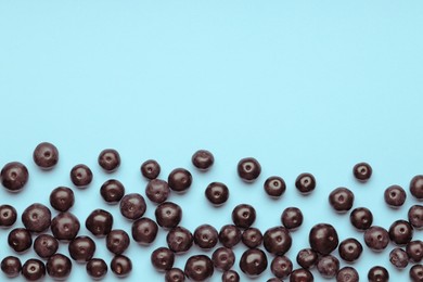 Photo of Ripe acai berries on light blue background, flat lay. Space for text