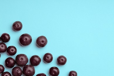 Photo of Ripe acai berries on light blue background, flat lay. Space for text