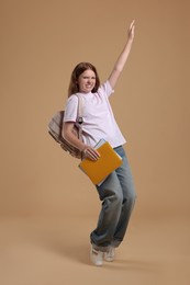 Photo of Teenage girl with backpack and books on beige background