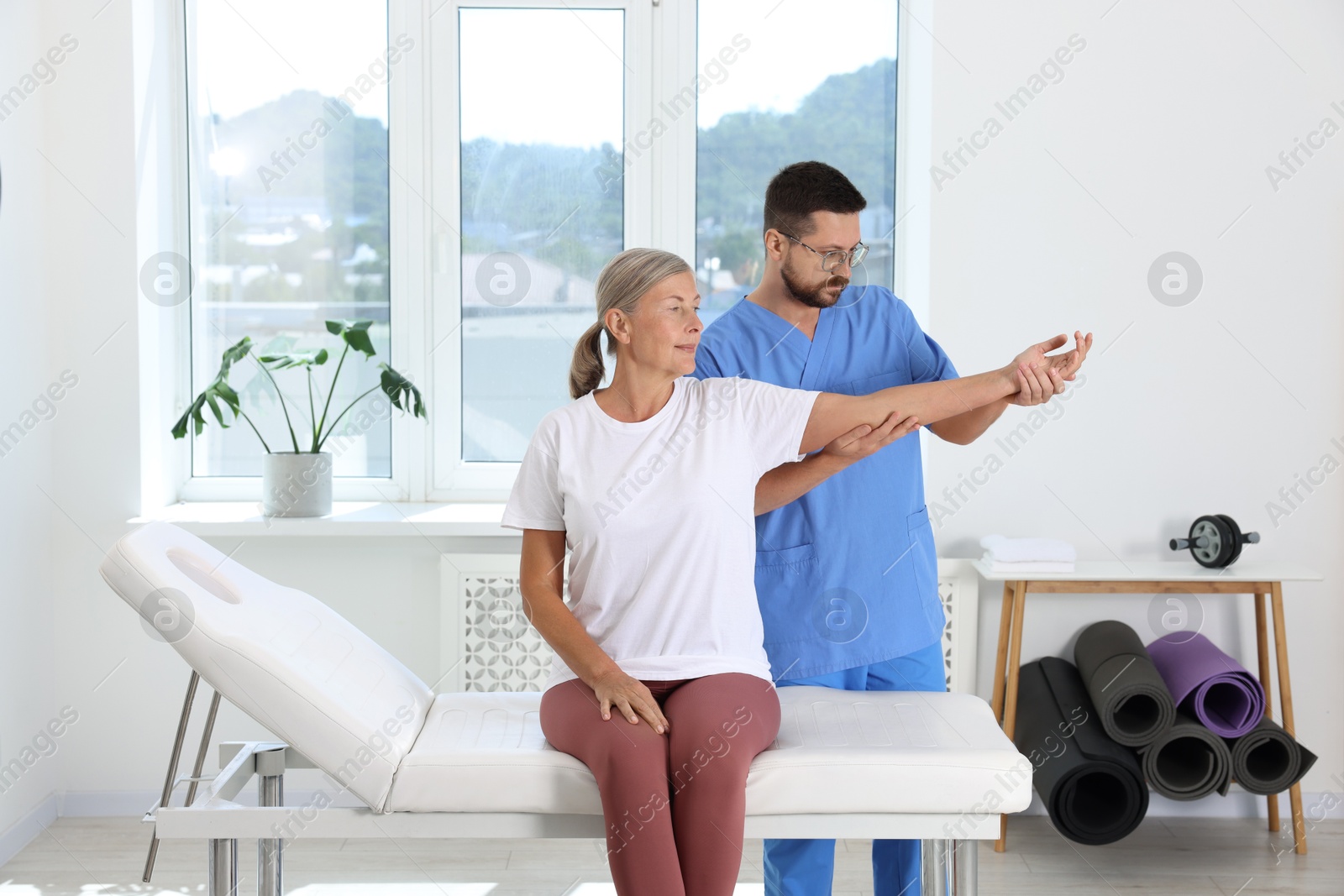 Photo of Physiotherapist working with senior patient in rehabilitation center