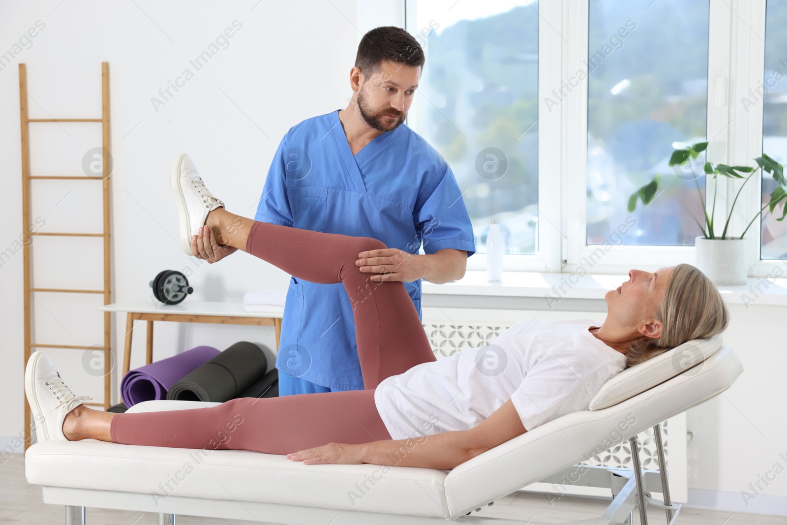 Photo of Physiotherapist working with senior patient in rehabilitation center