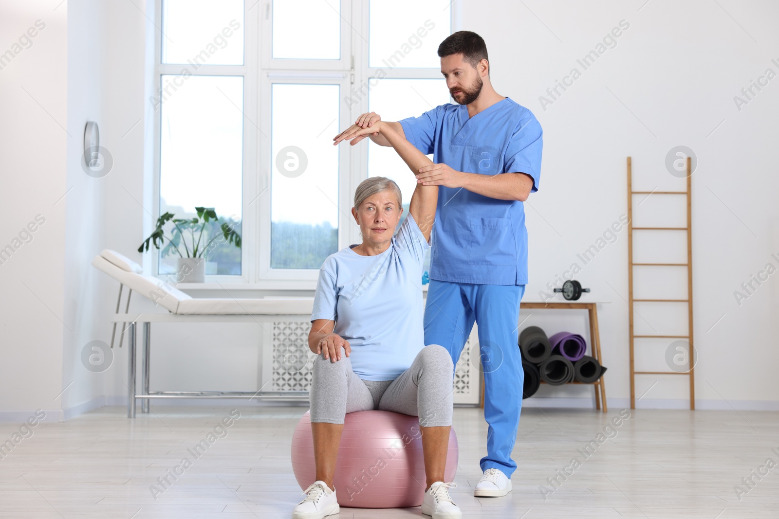 Photo of Physiotherapist working with senior patient in rehabilitation center