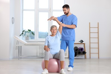 Photo of Physiotherapist working with senior patient in rehabilitation center