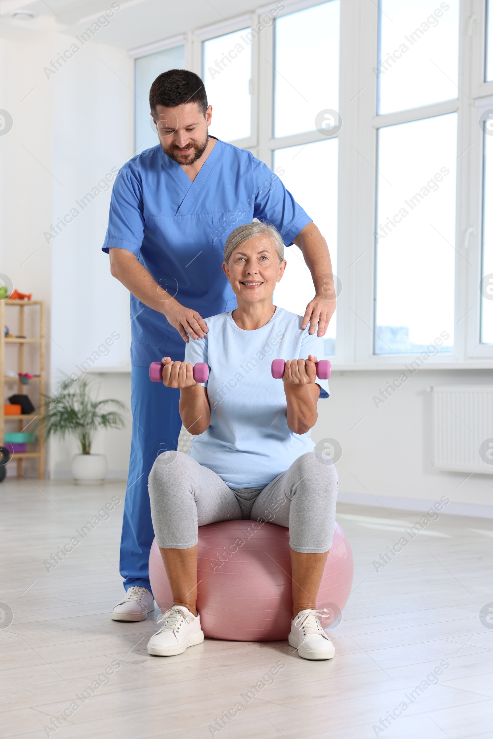 Photo of Senior patient exercising under physiotherapist supervision in rehabilitation center