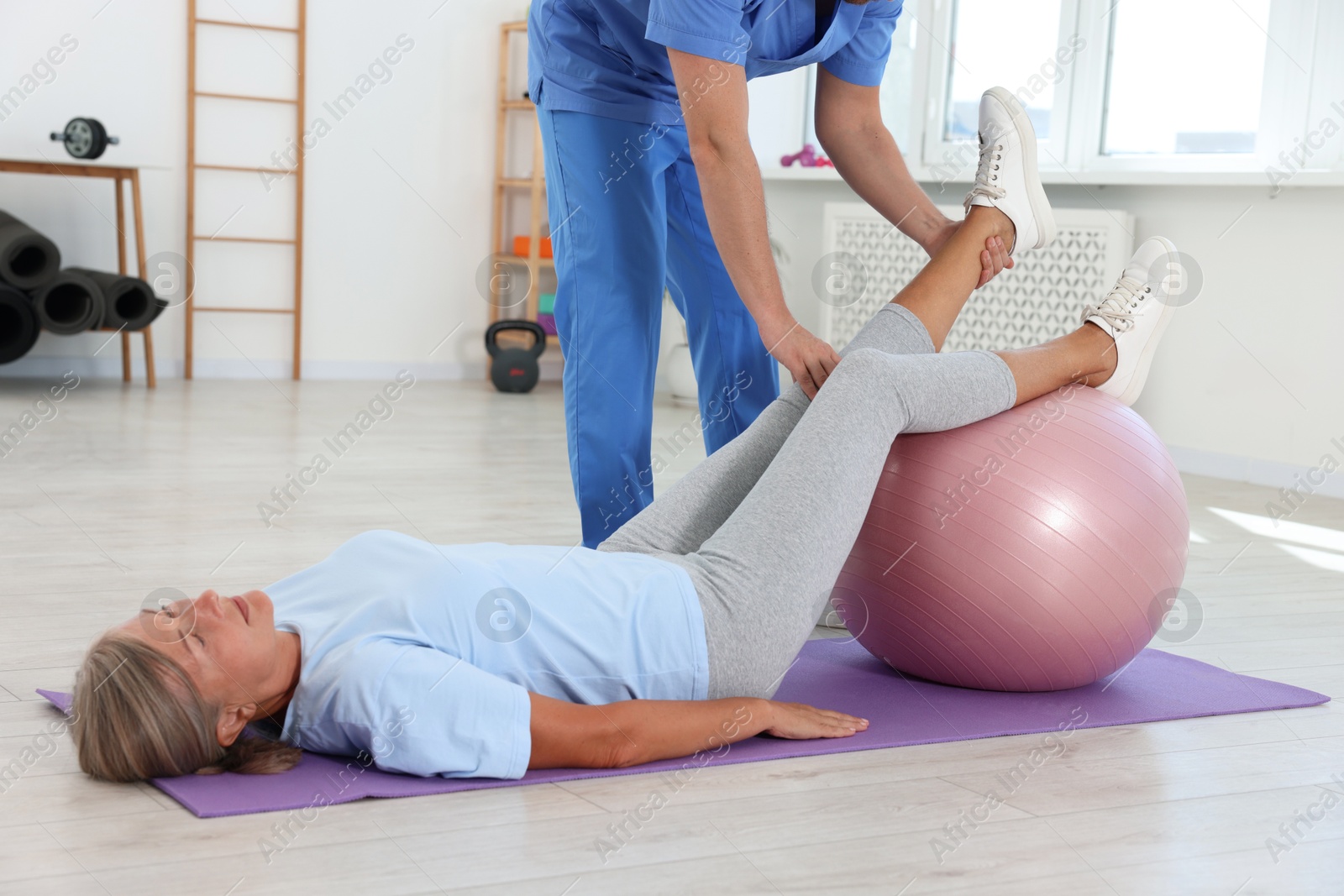 Photo of Physiotherapist working with senior patient in rehabilitation center