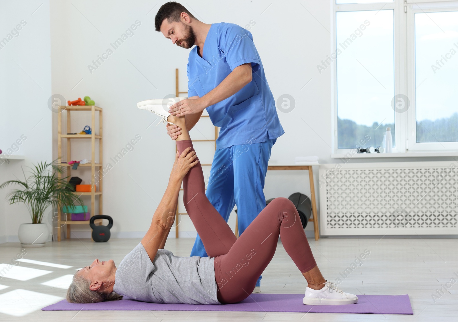 Photo of Physiotherapist working with senior patient in rehabilitation center