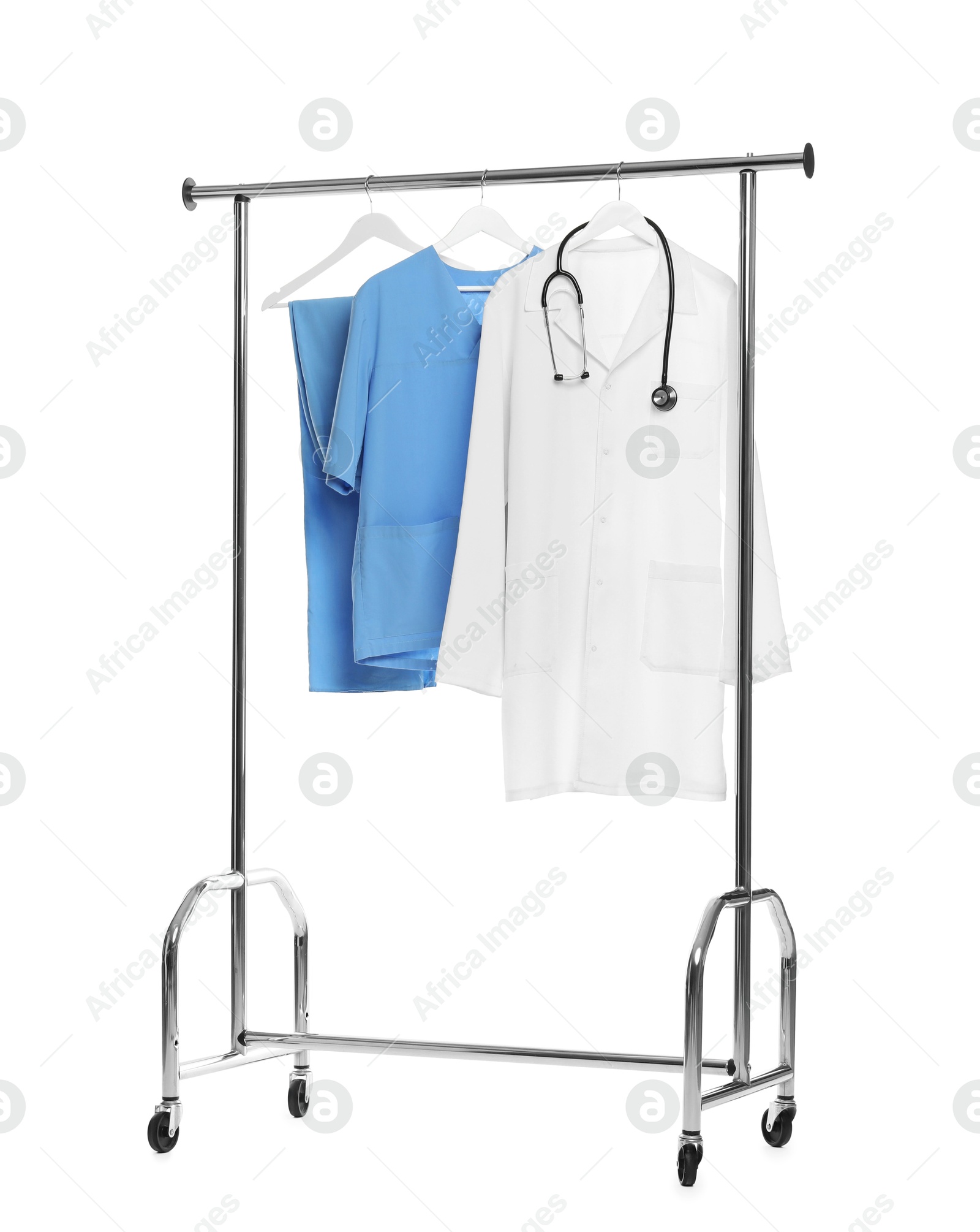 Photo of Different medical workers' uniforms and stethoscope on clothing rack against white background