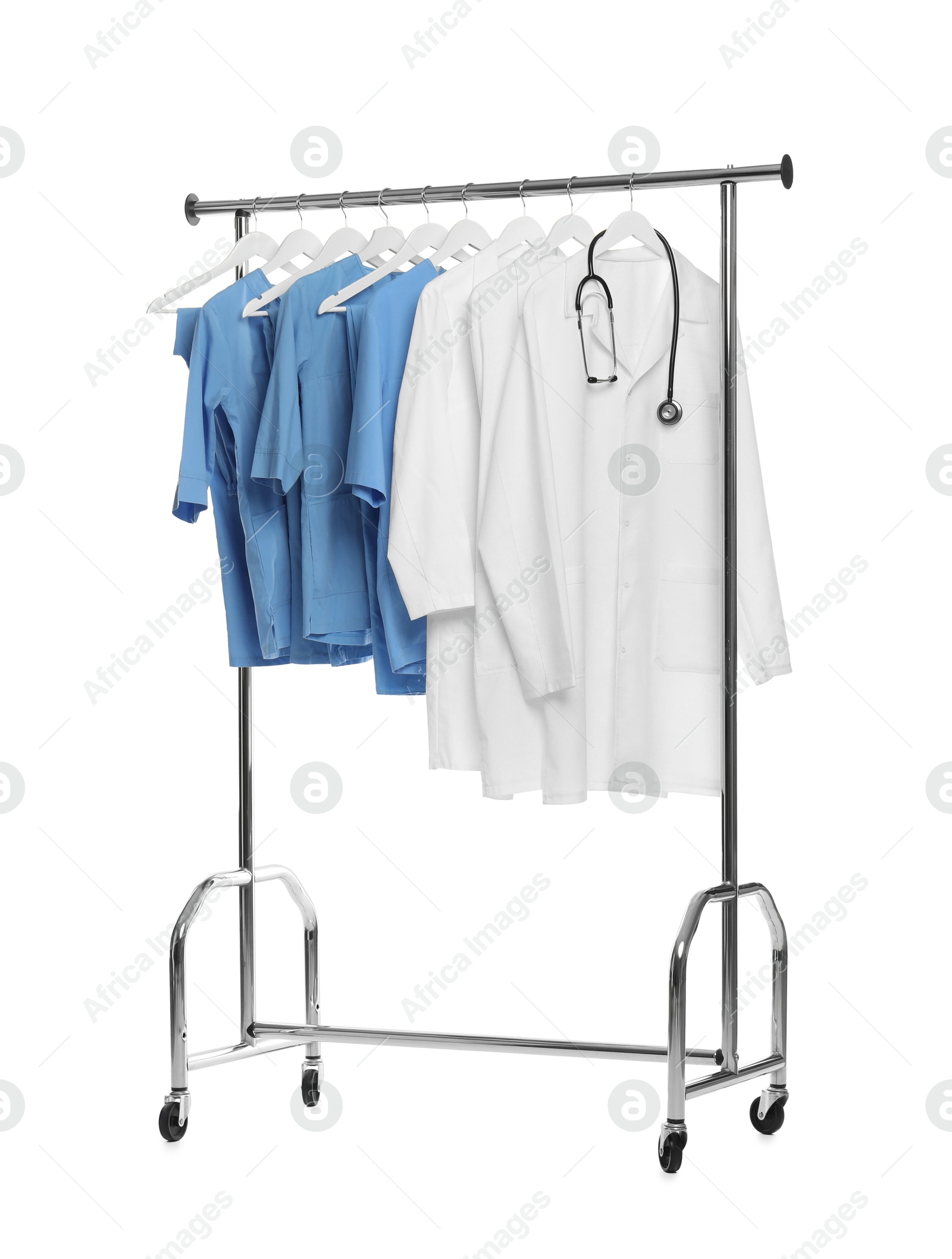 Photo of Different medical workers' uniforms and stethoscope on clothing rack against white background