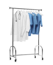 Photo of Different medical workers' uniforms and stethoscope on clothing rack against white background