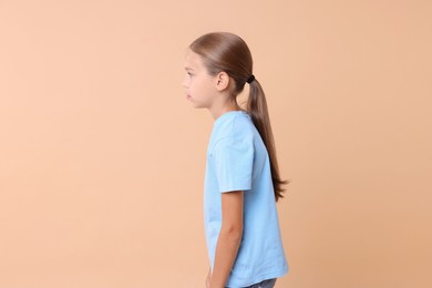 Girl with incorrect posture on beige background