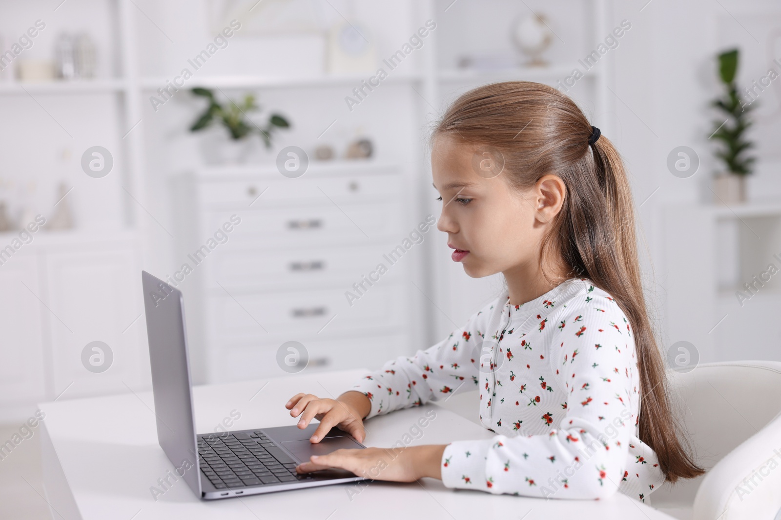 Photo of Girl with correct posture using laptop at white desk indoors