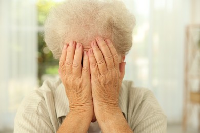 Photo of Senior woman closing her eyes with hands indoors