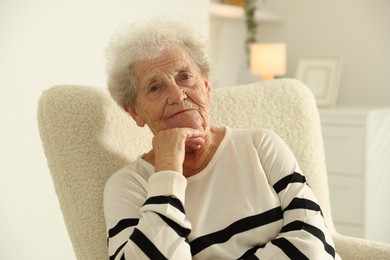 Beautiful senior woman sitting on armchair at home