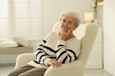 Beautiful senior woman sitting on armchair at home