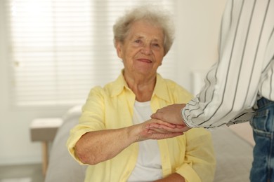 Senior woman holding hands with her granddaughter indoors, selective focus