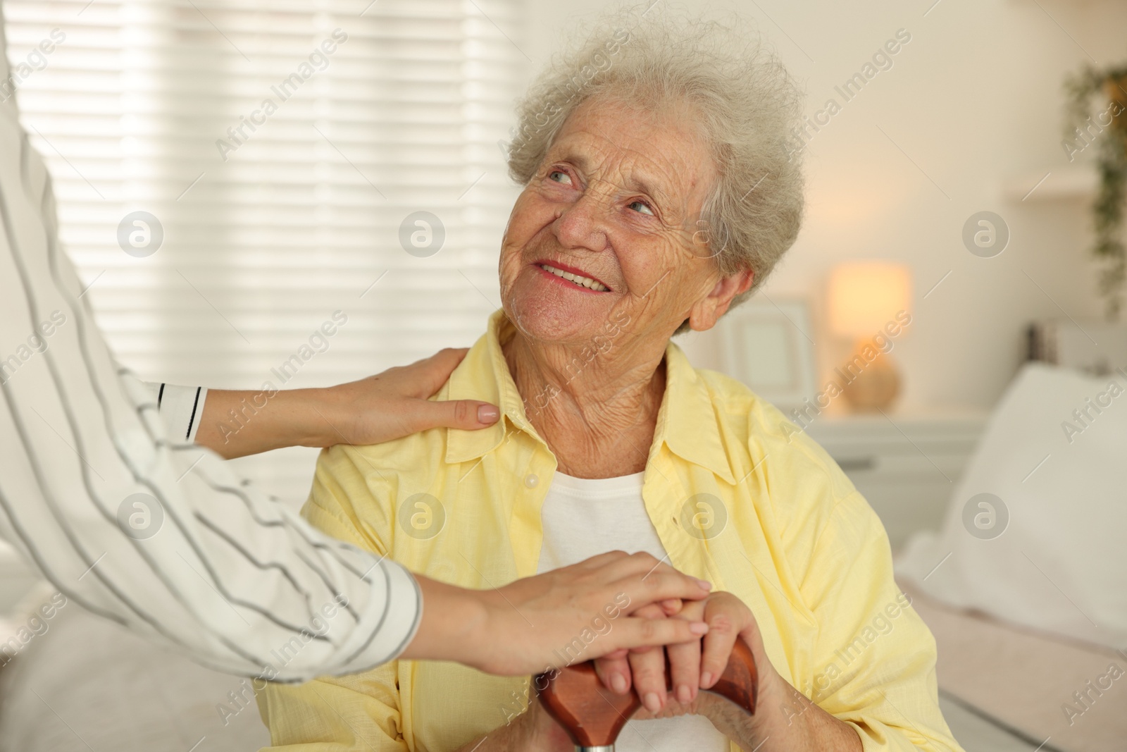 Photo of Senior woman with walking cane and her granddaughter at home